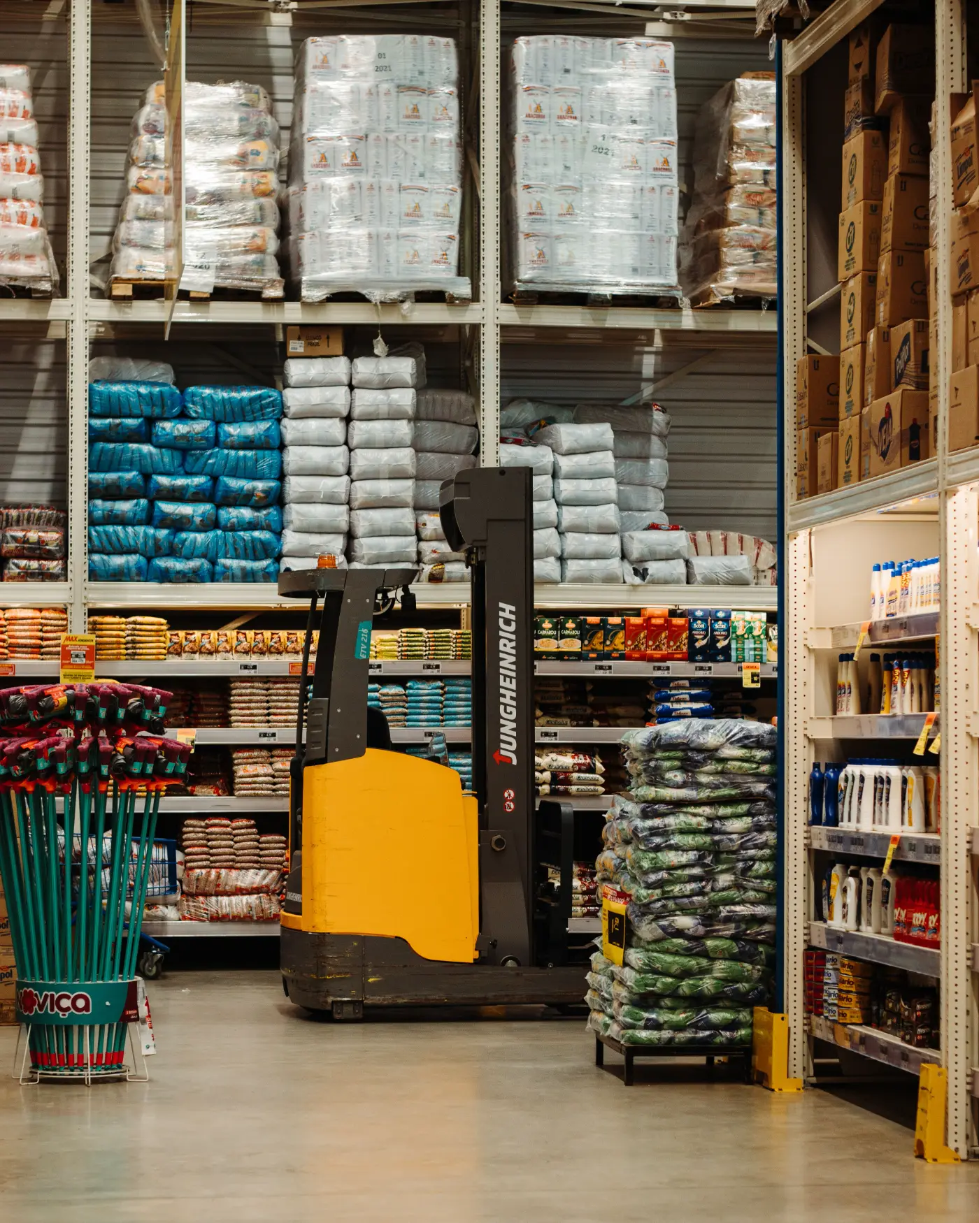 Stocked warehouse shelving with palletised goods and a pallet truck